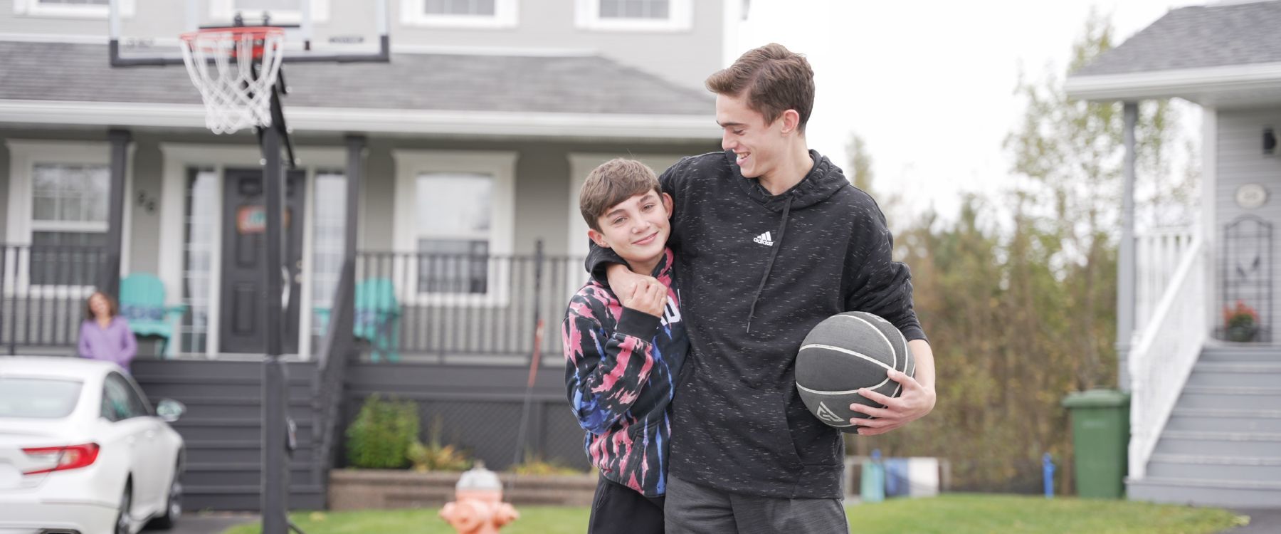 Ryan and Kyle Miller smiling while playing basketball outside in front of their family home